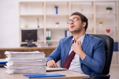 Young male employee and too much work in office