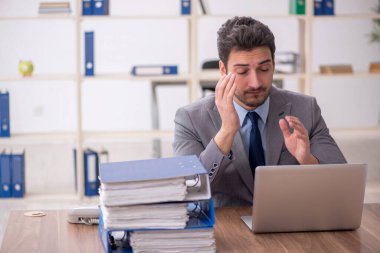 Young employee and too much work at workplace