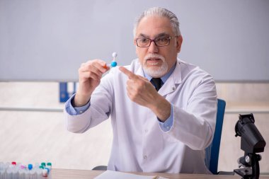 Old chemist teacher sitting in the classroom