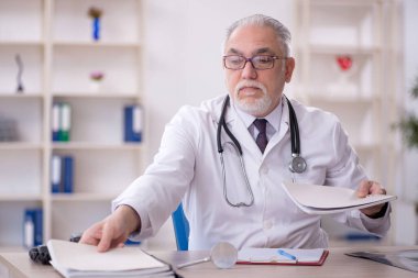 Klinikte çalışan yaşlı bir doktor.