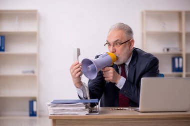 Ofiste elinde magafon tutan eski bir işadamı.