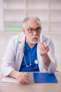 Hastanede çalışan yaşlı erkek doktor.