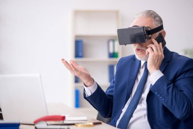 Old businessman employee wearing virtual glasses in the office