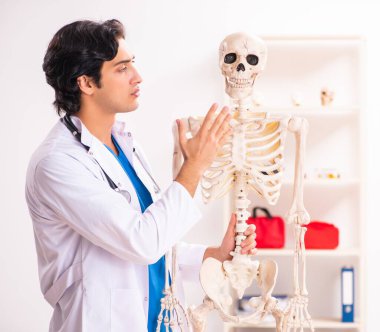 İskeleti olan genç erkek doktor.