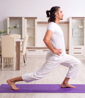 Genç adam evde fiziksel egzersiz yapıyor.