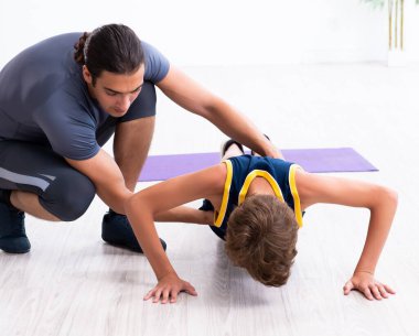 Genç baba ve oğlu egzersiz yapıyor.