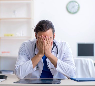 Klinikte çalışan genç erkek doktor.