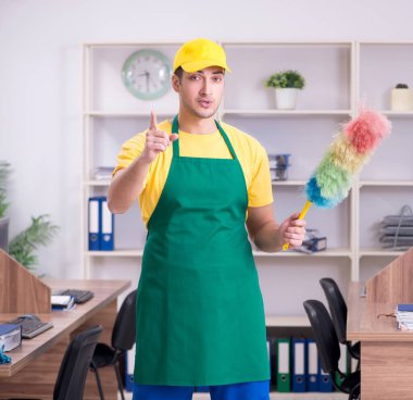 Genç erkek müteahhit ofisi temizliyor.