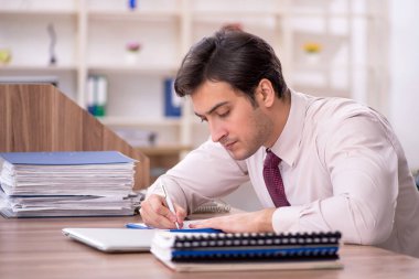 Genç işadamı ve işyerinde çok fazla iş var.