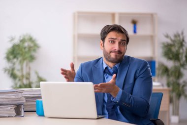 Genç işadamı ve işyerinde çok fazla iş var.