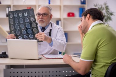 Genç hasta yaşlı doktoru ziyaret ediyor.