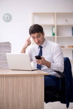 Young employee and too much work at workplace