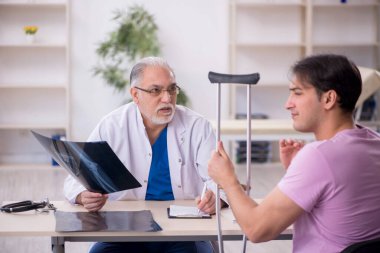 Genç bacak yaralı hasta yaşlı doktor radyolojisti ziyaret ediyor.