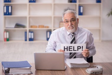 Old businessman employee unhappy with excessive work at workplace