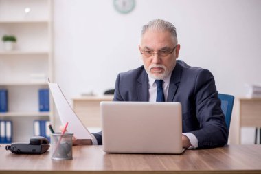 Old employee sitting at workplace