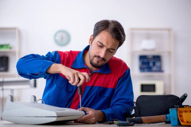 Genç tamirci atölyede ısıtıcıyı tamir ediyor.