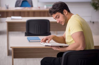 Young student teacher sitting in the classroom