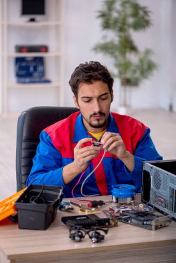 Atölyede bilgisayar tamir eden genç bir tamirci.