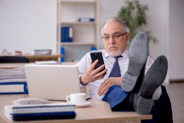 Old employee sitting at workplace