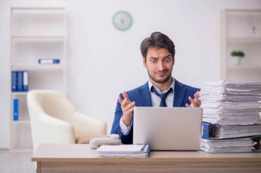 Young employee and too much work at workplace