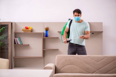 Genç müteahhit evde haşere kontrolü yapıyor.