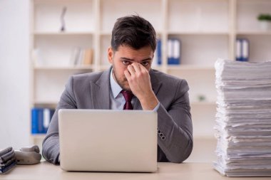Young employee and too much work at workplace