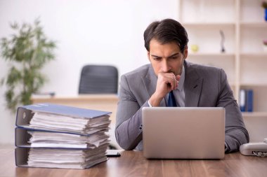 Genç işadamı ve işyerinde çok fazla iş var.