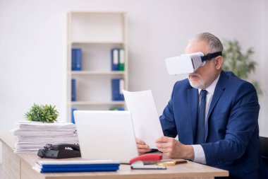 Old businessman employee wearing virtual glasses in the office