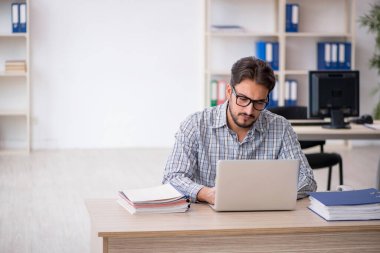 Genç erkek çalışan işyerinde oturuyor.