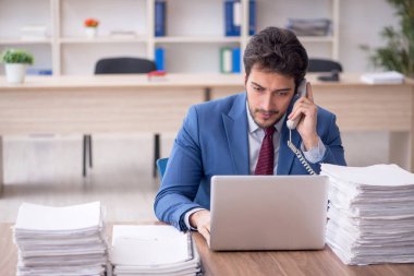 Young employee and too much work at workplace