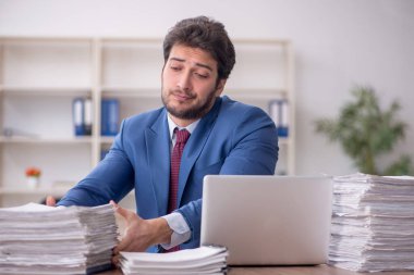 Young employee and too much work at workplace