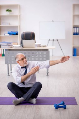 Eski erkek çalışanın teneffüste spor egzersizleri yapıyor.