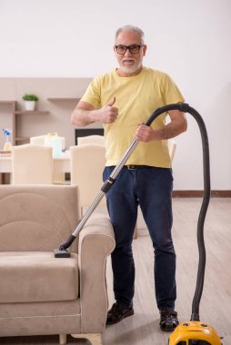 Yaşlı adam evi temizliyor.