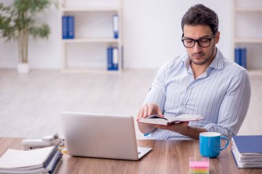 Young businessman employee reading book at workplace
