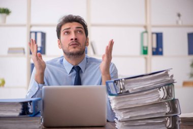Young employee and too much work at workplace
