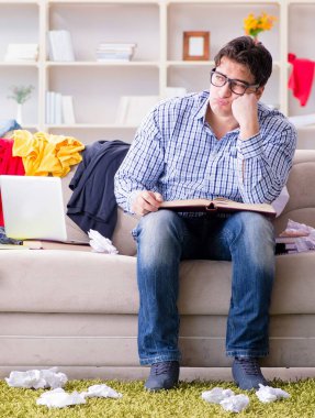 Dağınık odada çalışan genç adam.