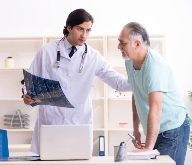 Yaşlı adam genç erkek doktoru ziyaret ediyor.