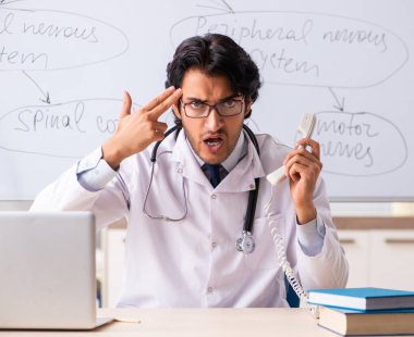 Beyaz tahtanın önündeki genç erkek doktor nörolog.