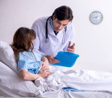 Erkek doktor koğuştaki kadın hastayı ziyaret ediyor.