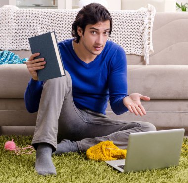 Evde örgü ören yakışıklı genç adam.