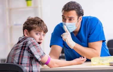 Genç çocuk hastanede doktoru ziyaret ediyor.