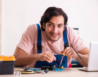Genç erkek müteahhit bilgisayarı tamir ediyor.