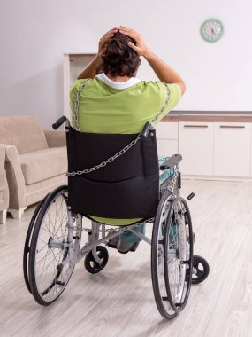 Evde acı çeken tekerlekli sandalyede yatalak genç erkek.