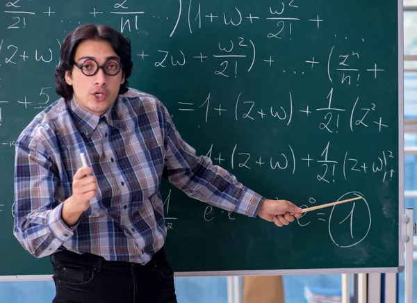 The young funny math teacher in front of chalkboard