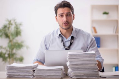 Young employee and too much work at workplace