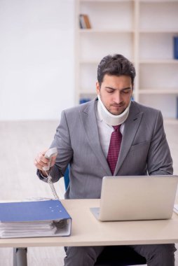 Young employee after car accident sitting at workplace