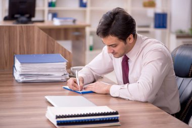 Genç işadamı ve işyerinde çok fazla iş var.