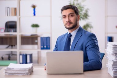 Genç bir çalışan ve ofiste çok fazla iş var.