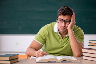 Sınıfta tahtaya oturan genç bir öğrenci.