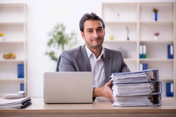 Stock image Young businessman employee and too much work in the office